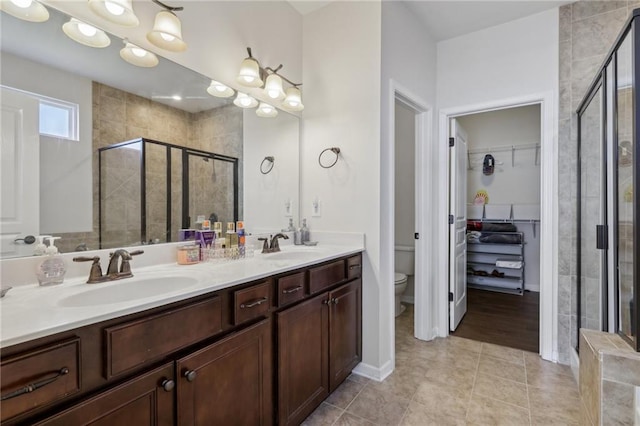 bathroom with toilet, double vanity, a sink, and a stall shower