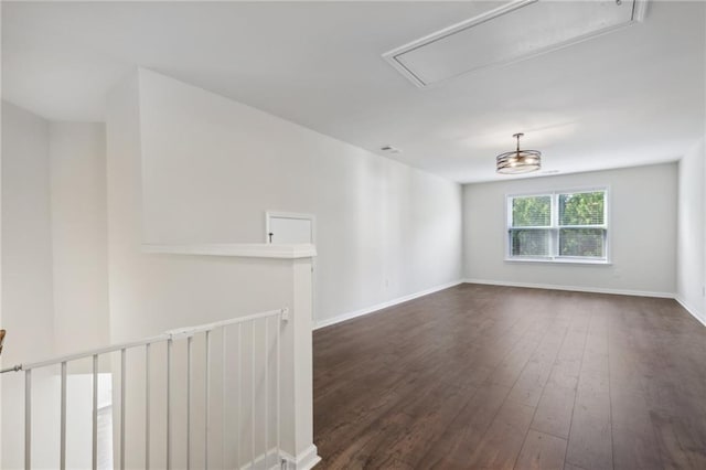 spare room with dark wood-type flooring, attic access, and baseboards