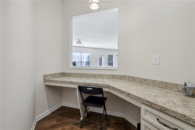 office area with dark wood-type flooring, built in study area, and baseboards