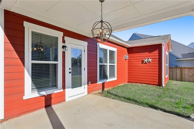 view of exterior entry featuring a yard and fence