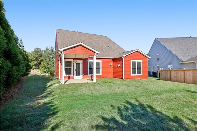 rear view of property featuring a yard and fence
