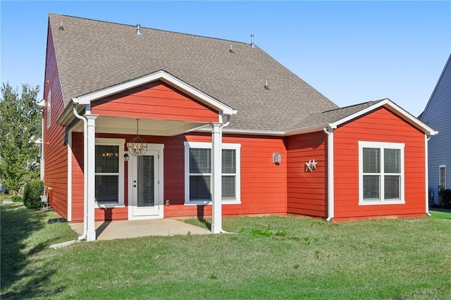 back of house featuring a shingled roof, a patio, and a lawn