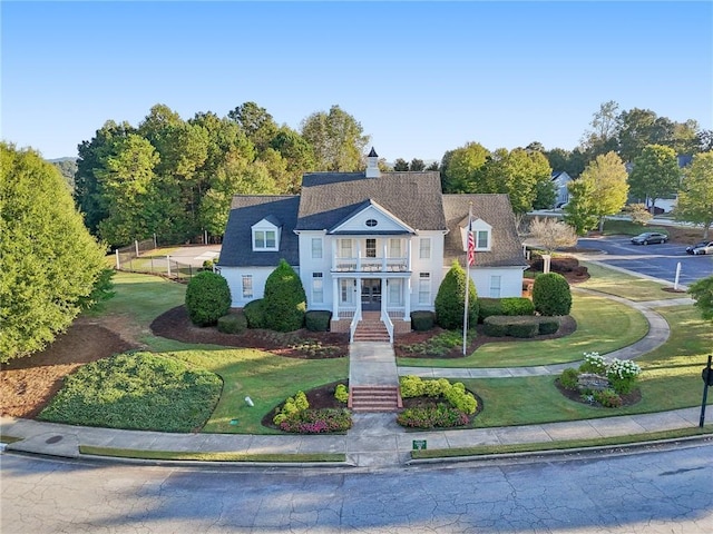 view of front of property featuring a front yard, fence, and a balcony