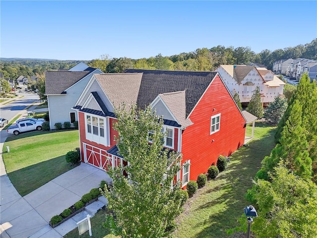 view of front facade with a shingled roof, a garage, concrete driveway, a front lawn, and a residential view
