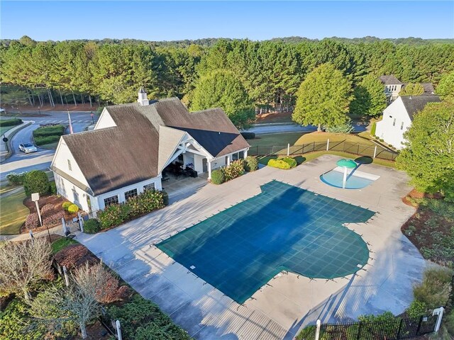 view of swimming pool with a wooded view and fence