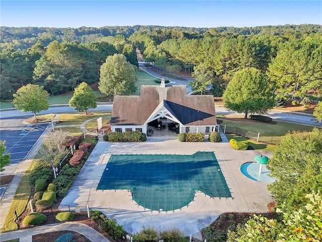 view of swimming pool with a view of trees, a patio, a covered pool, and fence