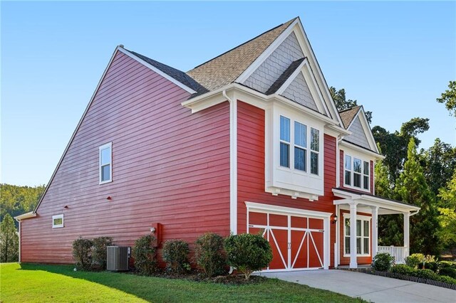 view of property exterior featuring a yard, driveway, central AC unit, and a garage