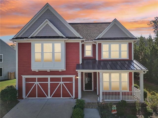 view of front of home with an attached garage, metal roof, a standing seam roof, and a porch