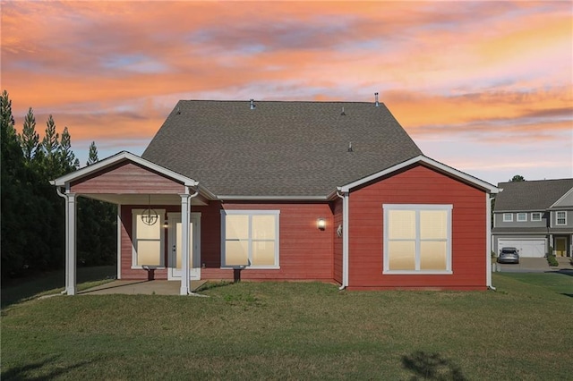 back of house at dusk featuring a yard