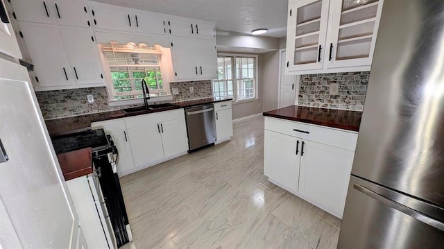 kitchen featuring appliances with stainless steel finishes, a sink, healthy amount of natural light, and decorative backsplash