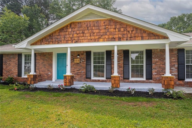 view of front of house with a porch, brick siding, and a front yard