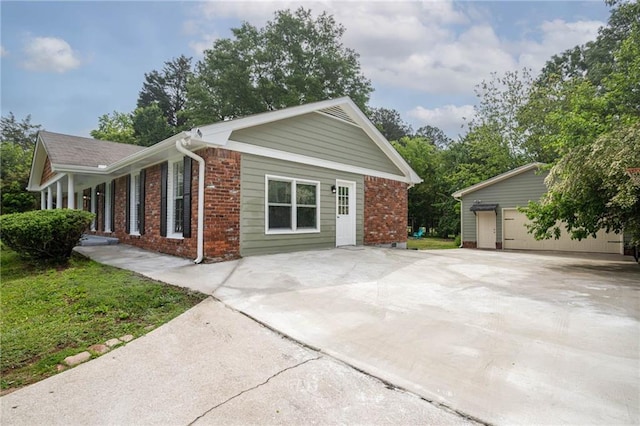 view of home's exterior with brick siding, an outdoor structure, and a detached garage