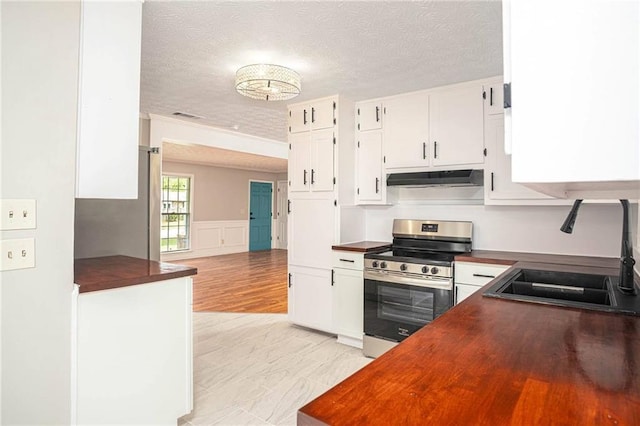 kitchen with stainless steel electric range, a sink, under cabinet range hood, a textured ceiling, and white cabinetry