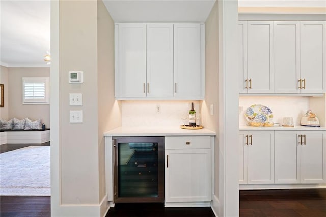 bar featuring dark wood-type flooring, white cabinetry, and beverage cooler