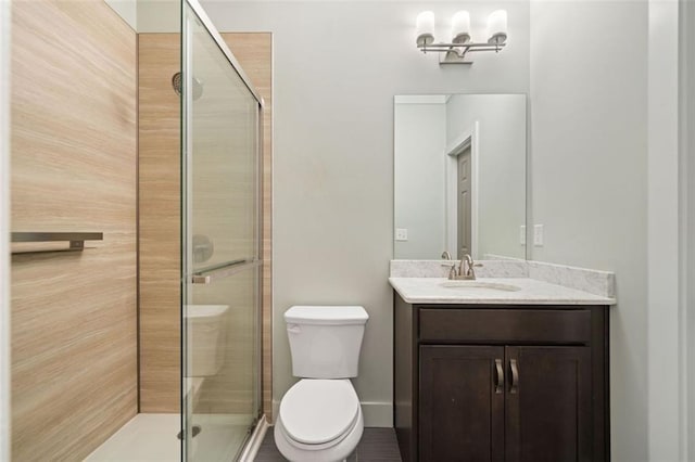 bathroom with toilet, vanity, and a shower with door