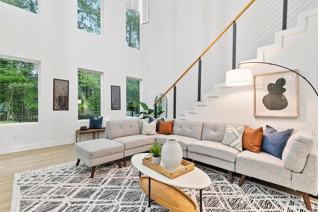 living room featuring a healthy amount of sunlight, a towering ceiling, and wood-type flooring