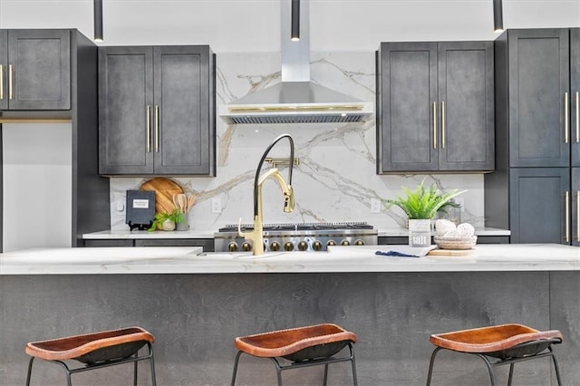 kitchen with decorative backsplash, a kitchen breakfast bar, extractor fan, and light stone countertops