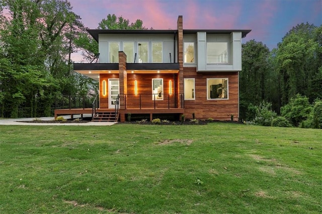 back house at dusk with a lawn and a porch