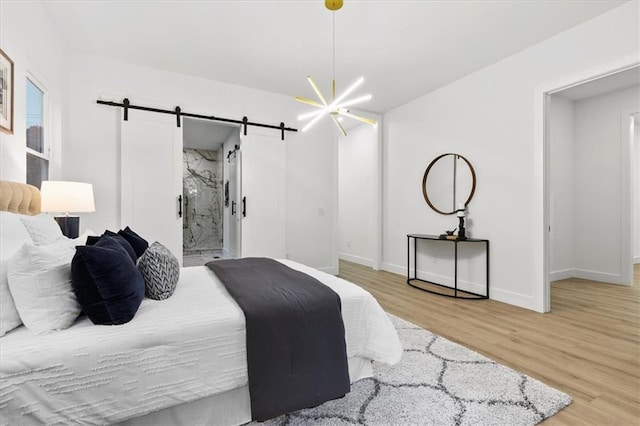 bedroom featuring a barn door, light hardwood / wood-style flooring, and ensuite bath