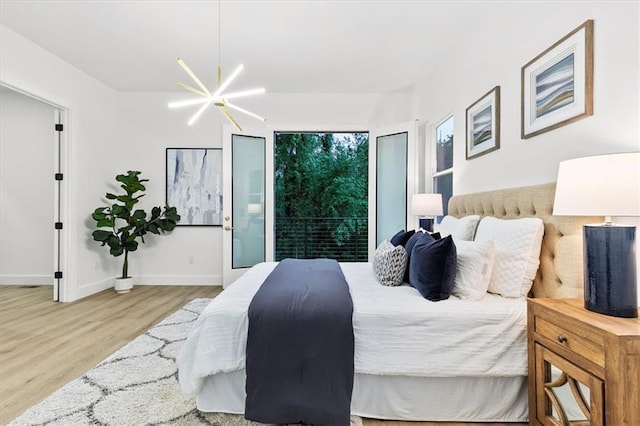 bedroom with access to exterior, light wood-type flooring, and a chandelier