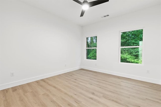 empty room with light hardwood / wood-style flooring, a wealth of natural light, and ceiling fan