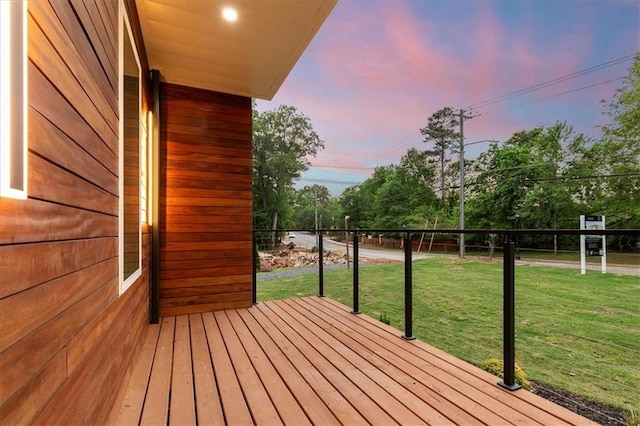 deck at dusk featuring a lawn