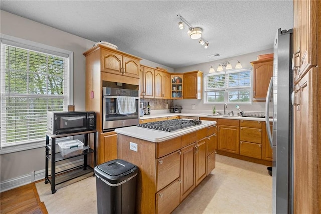 kitchen with sink, stainless steel appliances, a healthy amount of sunlight, and a kitchen island