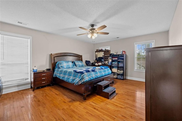 bedroom with ceiling fan, hardwood / wood-style flooring, and a textured ceiling