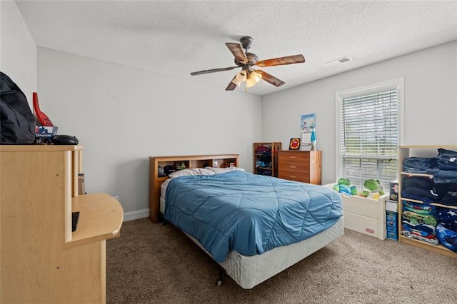 bedroom featuring ceiling fan, a textured ceiling, and dark carpet