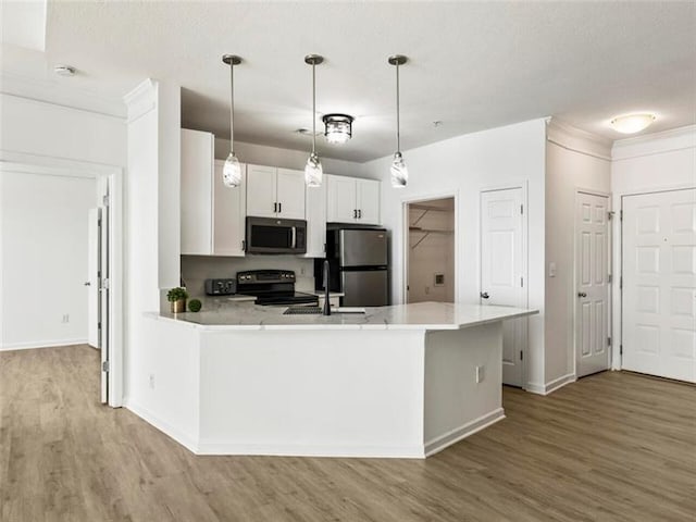 kitchen with light hardwood / wood-style floors, white cabinetry, pendant lighting, and appliances with stainless steel finishes