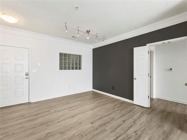 empty room with hardwood / wood-style flooring, ornamental molding, and rail lighting