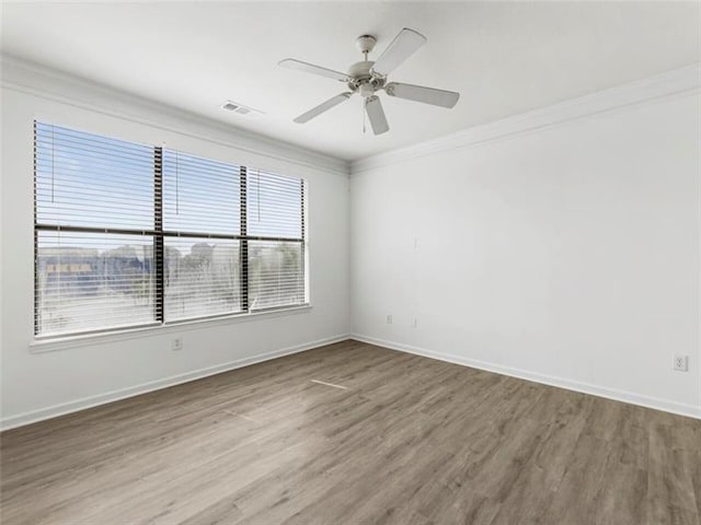 empty room with ceiling fan, wood-type flooring, and crown molding