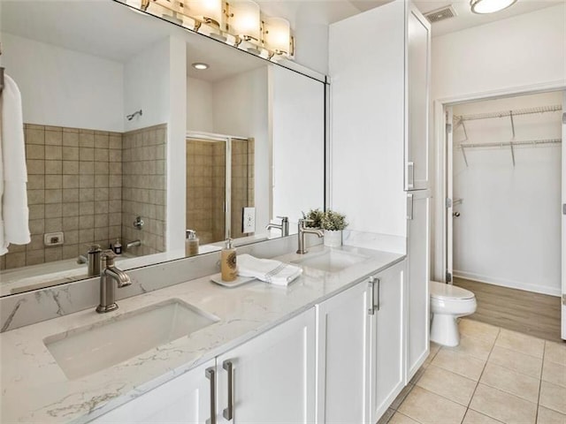 bathroom with tile patterned flooring, vanity, an enclosed shower, and toilet