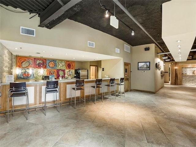 bar featuring a high ceiling and stainless steel refrigerator