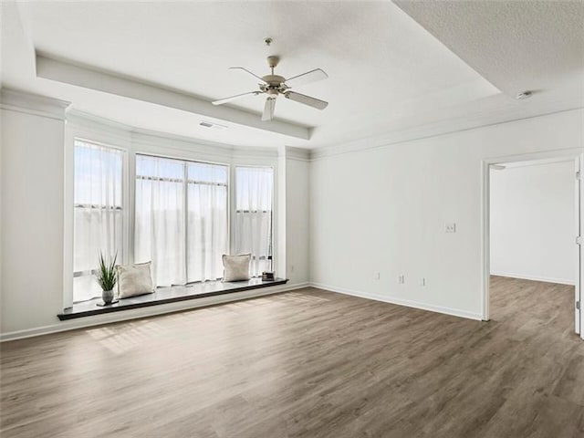 unfurnished room with a tray ceiling, ceiling fan, a textured ceiling, and dark hardwood / wood-style floors