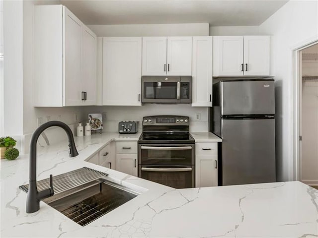 kitchen featuring white cabinetry, sink, light stone counters, and appliances with stainless steel finishes