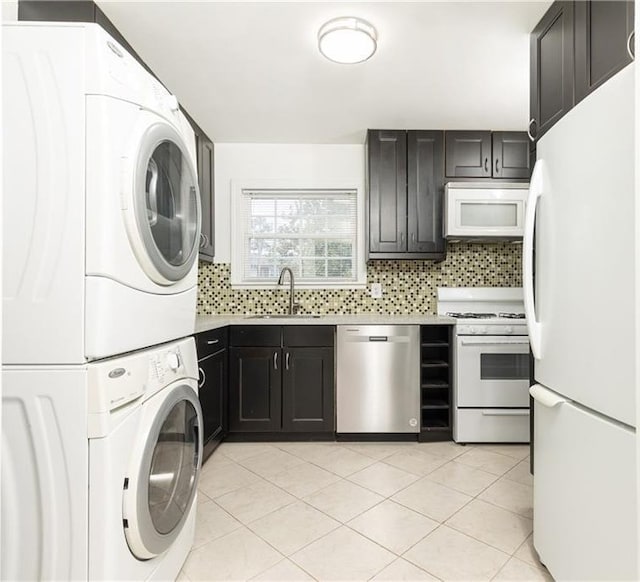 washroom featuring stacked washer and dryer, light tile patterned floors, dark brown cabinets, and sink