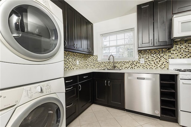 laundry area with stacked washer and dryer, light tile patterned flooring, and sink