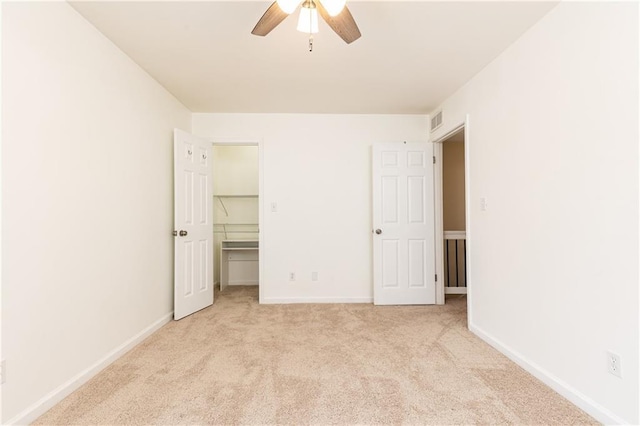 unfurnished bedroom featuring ceiling fan, a walk in closet, a closet, and light carpet