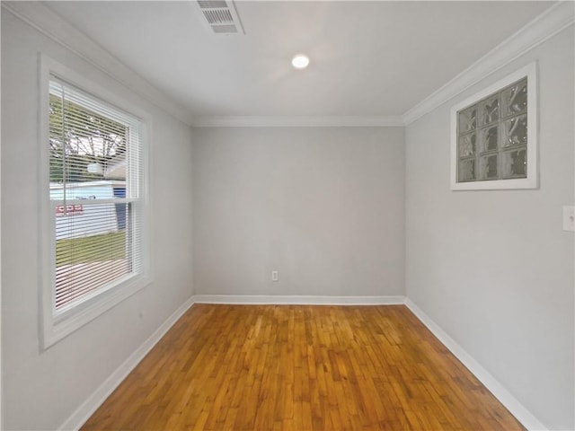 empty room with hardwood / wood-style flooring and crown molding