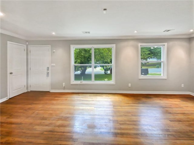 unfurnished room with wood-type flooring, crown molding, and plenty of natural light