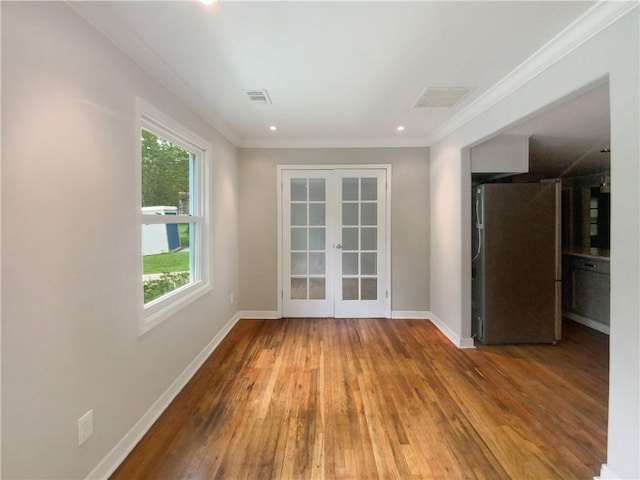 empty room with hardwood / wood-style floors, ornamental molding, and french doors