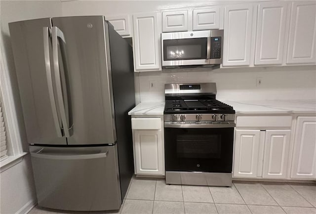 kitchen featuring stainless steel appliances, white cabinetry, light stone countertops, and light tile patterned floors