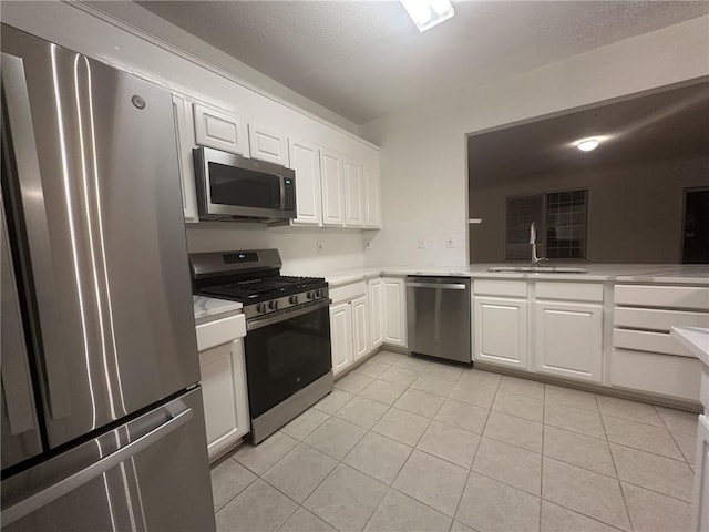 kitchen with sink, light tile patterned floors, stainless steel appliances, and white cabinets