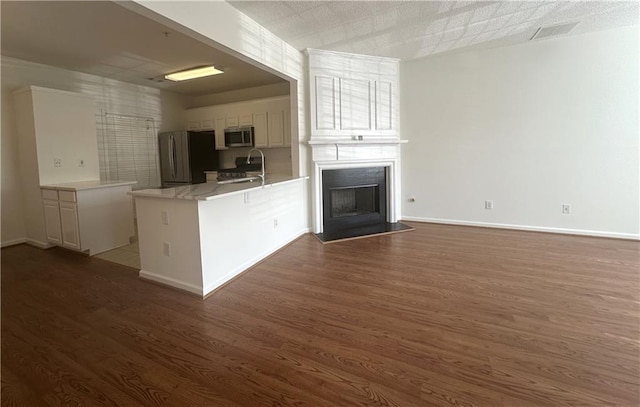 kitchen featuring dark hardwood / wood-style floors, kitchen peninsula, white cabinets, and appliances with stainless steel finishes