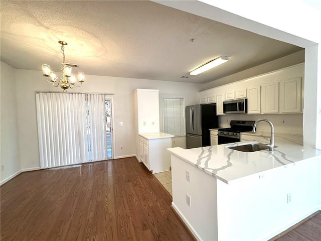 kitchen with appliances with stainless steel finishes, pendant lighting, white cabinets, and kitchen peninsula