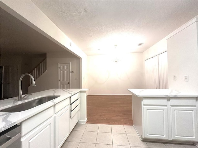 kitchen with white cabinetry, stainless steel dishwasher, light tile patterned flooring, and sink