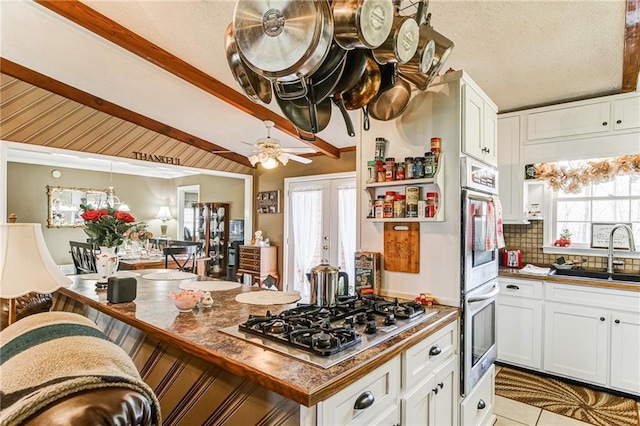 kitchen featuring ceiling fan, sink, stainless steel appliances, tasteful backsplash, and white cabinetry