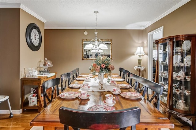 dining room featuring light hardwood / wood-style flooring, ornamental molding, a chandelier, and a textured ceiling