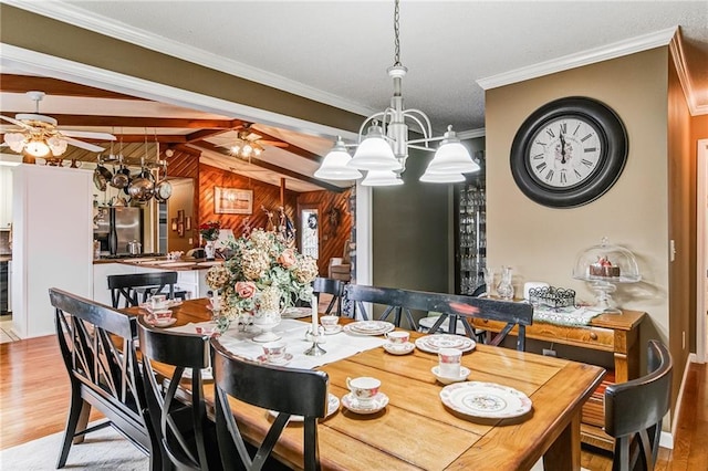 dining area featuring light hardwood / wood-style floors, wooden walls, ceiling fan with notable chandelier, and vaulted ceiling with beams